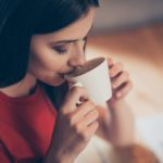 Crop photo of a girl who enjoys delicious aroma coffee with from