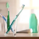 Glass with toothbrushes on wood table in bathroom general composition