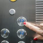 Woman in elevator or lift is pressing button to get into right floor only hand to be seen – close-up. 13 th floor