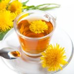 healthy dandelion tea with blossom in teacup on white background