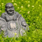 Figure of a Buddha sitting amid blooming clover.