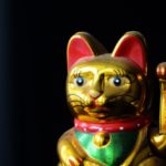 Golden Maneki Neko, the Lucky Cat, covered with dust. The concept of time and expectation of good luck