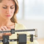 Woman Using Balance Weight Scale At Gym